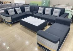 a couch and ottoman in a store with pillows on the top one is blue, while the rest of the couch has gold trim around it