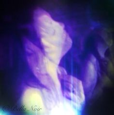 a blurry photo of a woman's face in purple and blue light with her eyes closed