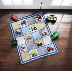 a baby's play mat with cars and trucks on it, sitting on the floor