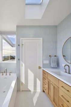 a bathroom with two sinks and a skylight above the bathtub is shown in this image