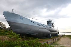 a large silver boat sitting on top of a lush green field