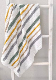 a blanket is hanging on the side of a white towel rack in front of a wall