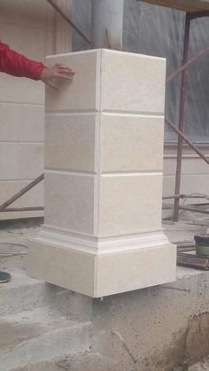 a man standing next to a tall white block in the middle of a building under construction