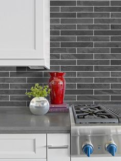 a red vase sitting on top of a kitchen counter next to a stovetop oven