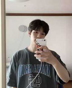 a young man taking a selfie in front of a mirror with his cell phone