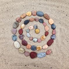 several rocks arranged in the shape of a spiral on top of some sand and water