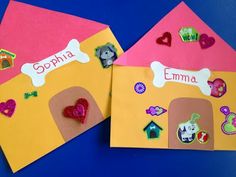 two children's handmade paper houses with dogs and bones on them, one is pink and the other is yellow