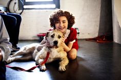 a woman is sitting on the floor with her dog and smiling at the camera man