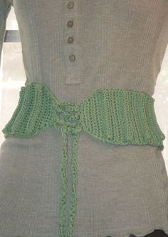 a woman's sweater with a green crochet belt attached to the front