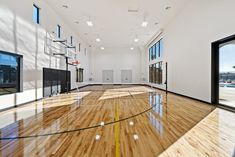 an indoor basketball court with hard wood floors and glass doors leading to the other side