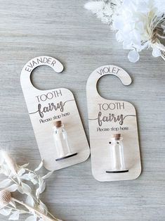 two wooden bottle openers with tooth fairy written on them and some flowers in the background