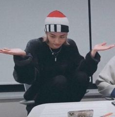 a woman sitting at a table wearing a santa hat and holding her hands out to the side