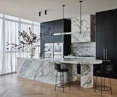 an elegant kitchen with marble counter tops and black cabinets, along with bar stools