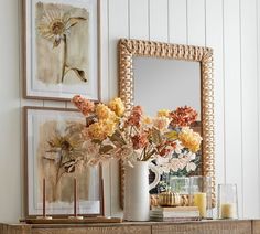 a vase filled with flowers sitting on top of a wooden table next to a mirror