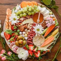 a platter filled with assorted fruits and veggies on top of a wooden table