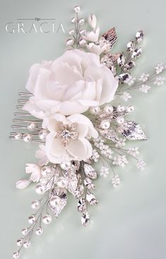 a bridal hair comb with white flowers and pearls on the front, attached to a light green background