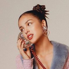 a woman talking on a cell phone while wearing a fur vest and holding a telephone to her ear