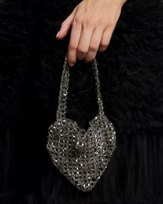 a woman's hand holding onto a black purse with silver sequins on it