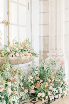 an arrangement of flowers on a table in front of a window