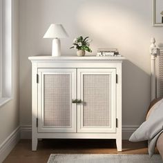 a white cabinet sitting in the corner of a room next to a bed and lamp