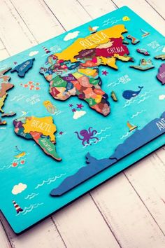 a wooden map of the world is shown on a white wood floor with blue background