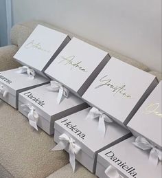 four boxes with white bows are stacked on top of each other and labeled with names