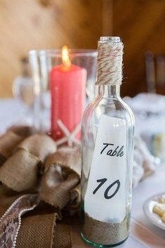 a bottle with a table number on it sitting next to a candle and some crackers