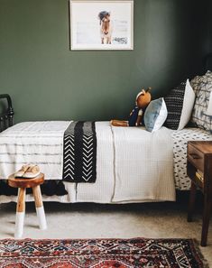 a bedroom with green walls and white bedding, wooden stools on the floor