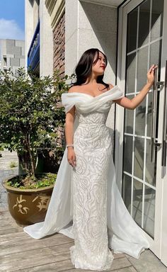 a woman in a white dress standing on a porch