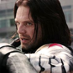 a close up of a person with long hair wearing armor and holding something in his hand