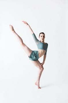 a woman is doing a dance move in front of a white background with her legs spread out