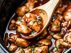 a wooden spoon full of chicken and mushrooms with sauce in the slow cooker, ready to be eaten