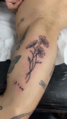 a woman's leg with tattoos and flowers on it