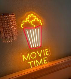 a neon sign that says movie time next to a chandelier on a wall