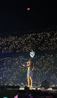 a woman standing on top of a stage in front of a crowd at a concert