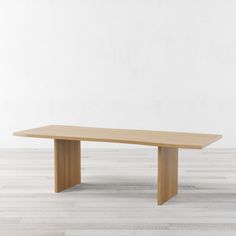 a wooden table sitting on top of a white floor next to a wall in an empty room