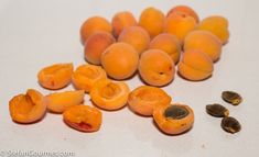 peeled apricots and seeds on a white surface