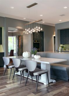 a dining room table and chairs with lights hanging from the ceiling