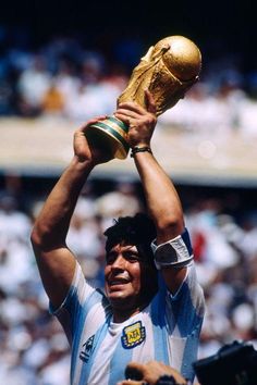 a man holding up a golden trophy in front of a crowd at a sporting event