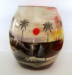 an artistic vase with palm trees painted on it's sides and a red dot in the middle