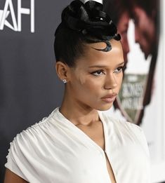 a close up of a person wearing a white dress and black hair with a bun