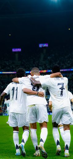 a group of soccer players huddle together on the field in front of an empty stadium