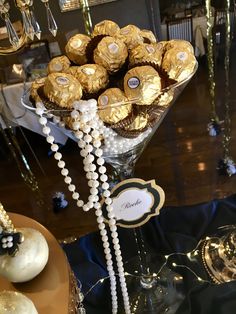 a glass vase filled with lots of chocolates on top of a table next to other items