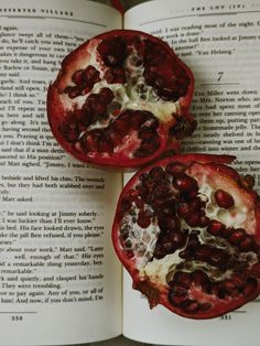 two pomegranates sitting on top of an open book