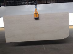 a piece of white marble sitting on top of a floor next to a crane in a warehouse