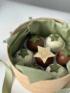 a wooden bowl filled with assorted chocolates on top of a green satin ribbon