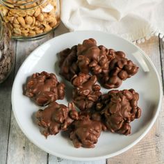 chocolate covered cookies on a white plate next to nuts