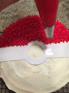 someone is decorating a cake with red icing