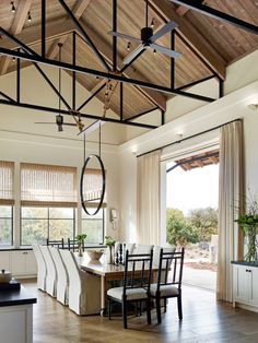 a dining room table and chairs in front of a large window with wooden ceiling beams