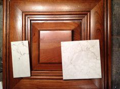 two square marble tiles sitting on top of a wooden paneled wall next to each other